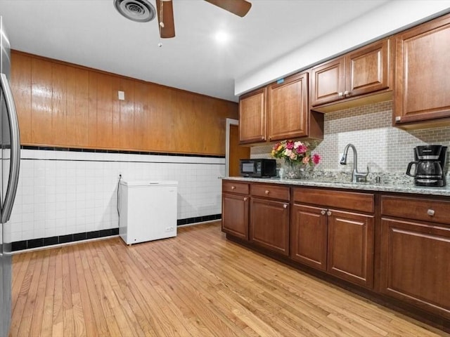 273 Elm St, Southbridge, MA 01550 - kitchen with black microwave, refrigerator, ceiling fan, light wood-style flooring, and light stone counters