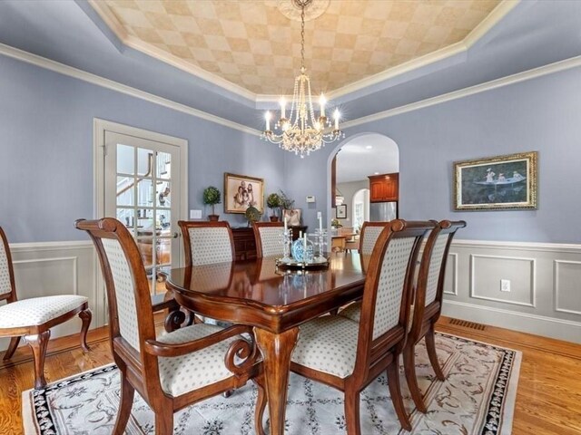 35 Oxbow Dr, Wrentham, MA 02093 - dining area with arched walkways, ornamental molding, a raised ceiling, a chandelier, and light wood-style floors
