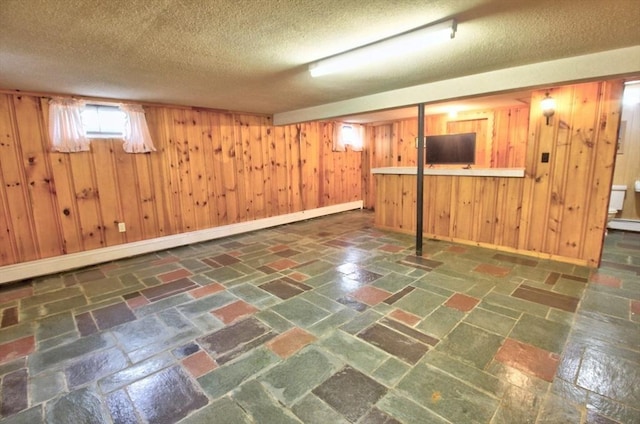 31 Lee Ave, Fitchburg, MA 01420 - below grade area featuring wooden walls, a textured ceiling, baseboards, and baseboard heating