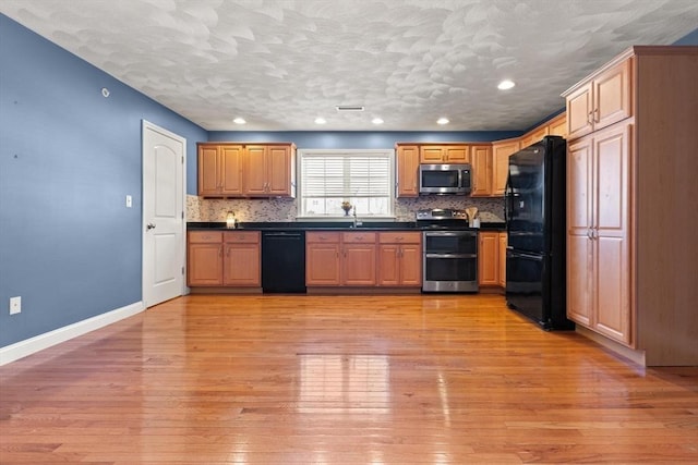 kitchen featuring sink, light wood-type flooring, black appliances, and backsplash