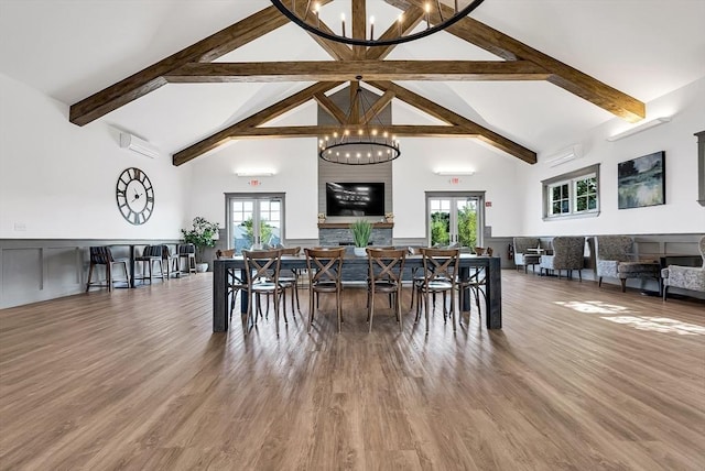 dining area with french doors, a wall mounted air conditioner, high vaulted ceiling, a notable chandelier, and wood-type flooring