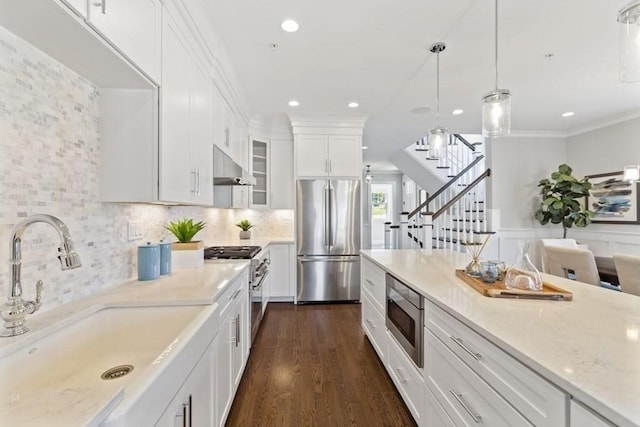 kitchen featuring light stone countertops, white cabinetry, sink, stainless steel appliances, and crown molding