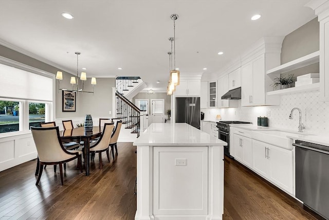 kitchen with sink, hanging light fixtures, stainless steel appliances, a kitchen island, and white cabinets