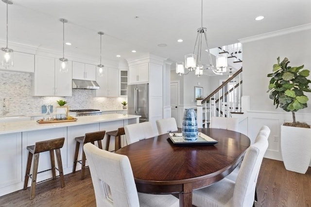 dining area with dark hardwood / wood-style floors, an inviting chandelier, ornamental molding, and sink