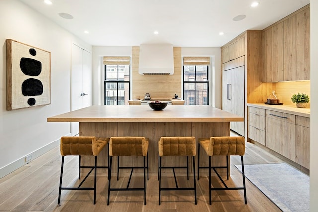 kitchen featuring light brown cabinetry, a kitchen island, light wood-type flooring, and paneled built in refrigerator