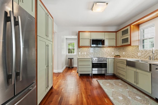 17 Perry St, Somerville, MA 02143 - kitchen featuring appliances with stainless steel finishes, green cabinetry, dark wood-style floors, light countertops, and decorative backsplash