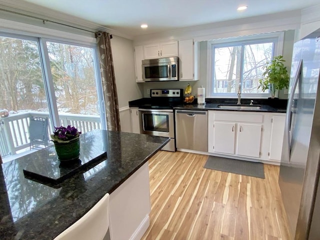 kitchen featuring stainless steel appliances, sink, light hardwood / wood-style flooring, dark stone countertops, and white cabinets