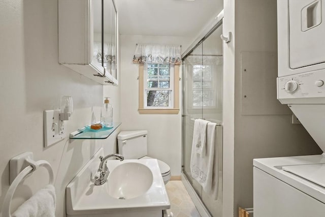 bathroom with toilet, baseboards, stacked washing maching and dryer, a shower stall, and a sink