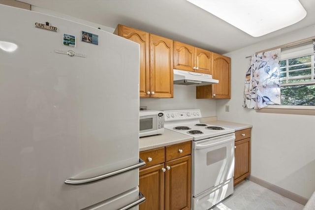 kitchen featuring white appliances, baseboards, light countertops, under cabinet range hood, and brown cabinets