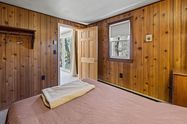 bedroom with access to outside, carpet, and wooden walls