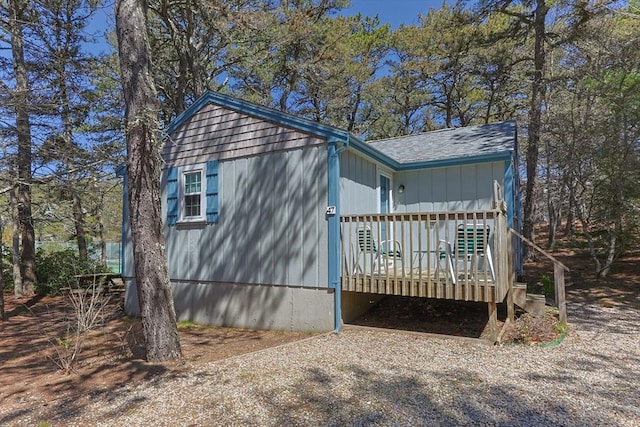 view of side of home featuring a deck and a shingled roof