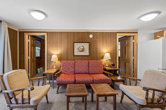 carpeted living area featuring wood walls