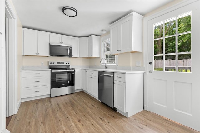 23 Lenox Cir, Lawrence, MA 01843 - kitchen with stainless steel appliances, light countertops, light wood-style floors, white cabinets, and a sink