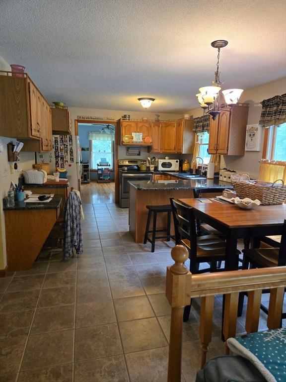 127 Parker Ln, Ludlow, MA 01056 - dining room featuring a chandelier, dark tile patterned flooring, and a textured ceiling