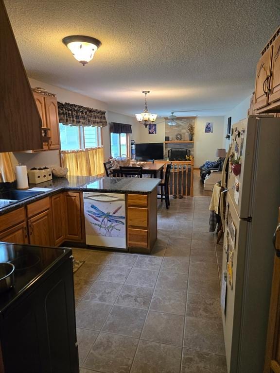127 Parker Ln, Ludlow, MA 01056 - kitchen with white appliances, dark countertops, a textured ceiling, a peninsula, and brown cabinetry