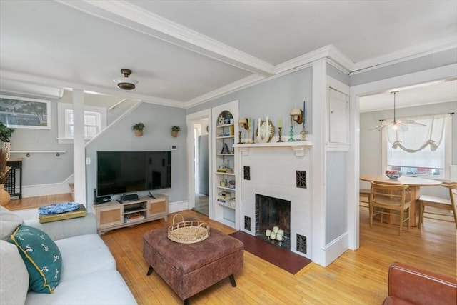 living area featuring wood-type flooring, a healthy amount of sunlight, stairs, and crown molding