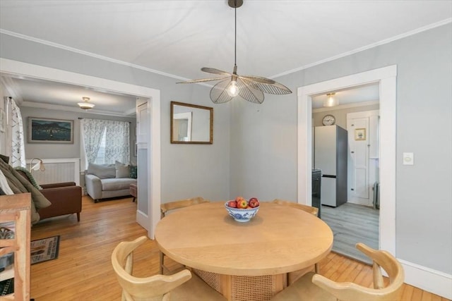 dining space featuring crown molding, light wood-style flooring, and baseboards