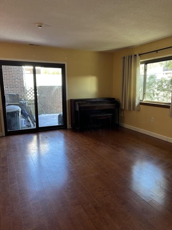 unfurnished living room featuring dark wood-style floors and baseboards