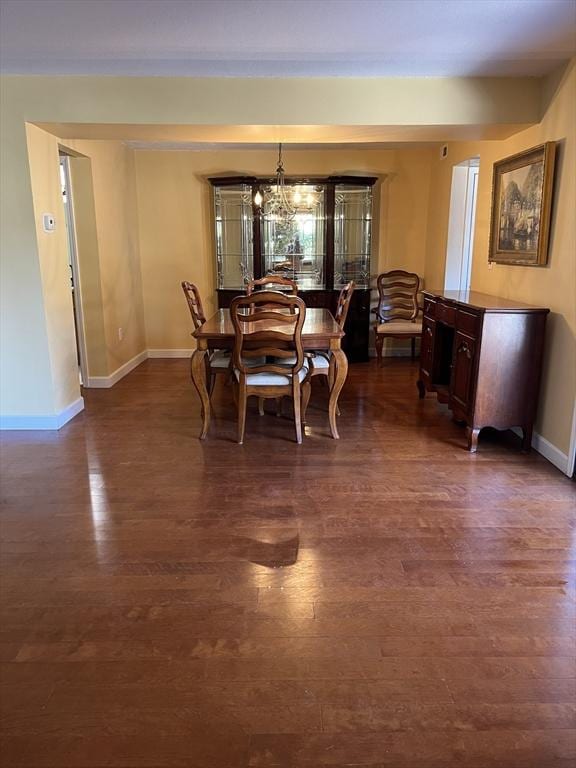 dining space featuring a chandelier, dark wood-style flooring, and baseboards