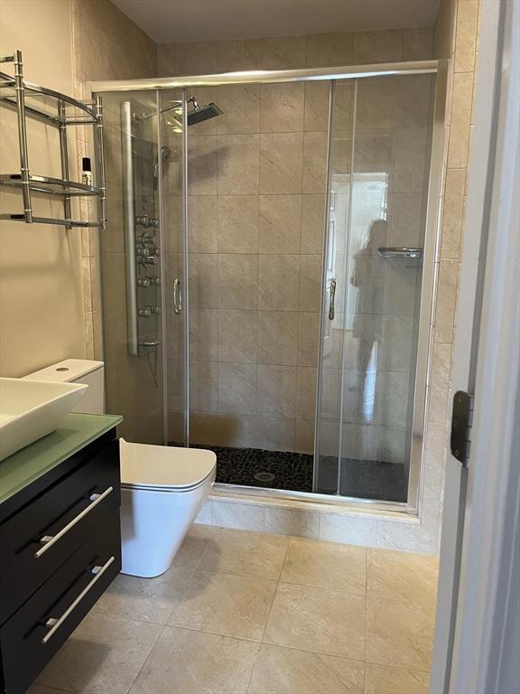 full bath featuring toilet, a shower stall, and vanity