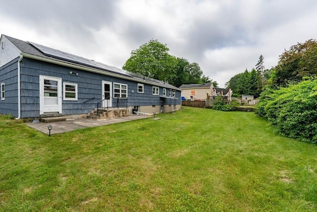 46 Birchland Ave, Springfield, MA 01119 - back of property featuring entry steps, a yard, roof mounted solar panels, and a patio