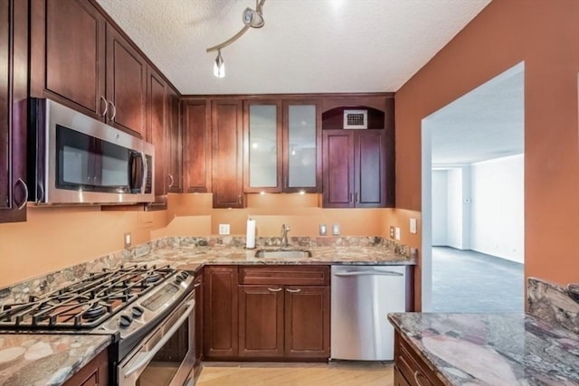 99 Pond Ave Unit 608, Brookline, MA 02445 - kitchen featuring stainless steel appliances, light stone countertops, a textured ceiling, and glass insert cabinets