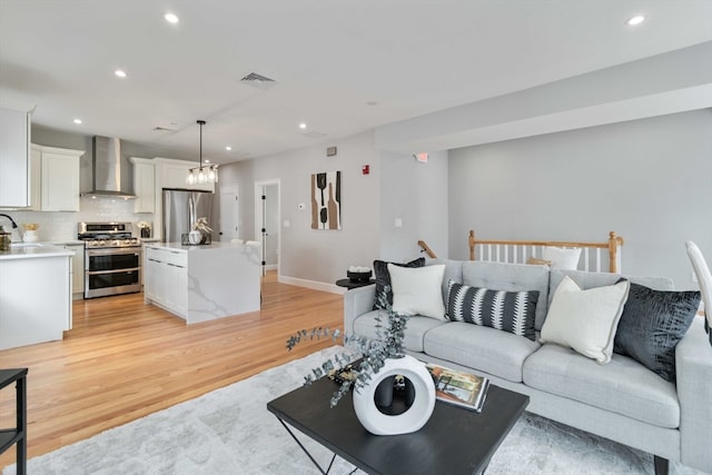 living room featuring a chandelier, sink, and light wood-type flooring