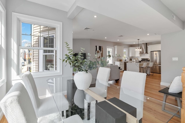 dining room with sink, a chandelier, and light hardwood / wood-style floors