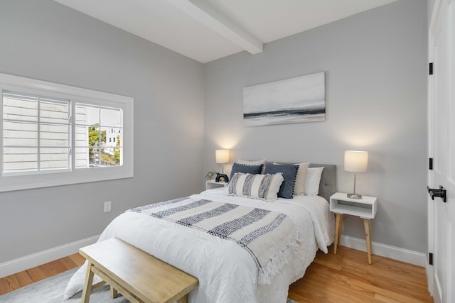 bedroom with wood-type flooring and beam ceiling