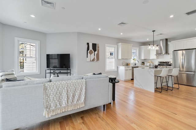 living room featuring light wood-type flooring, a chandelier, and sink