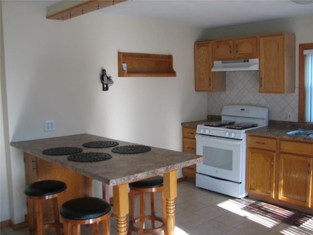 436 Brown St, Attleboro, MA 02703 - kitchen featuring white range with gas stovetop, under cabinet range hood, tasteful backsplash, a kitchen bar, and a peninsula