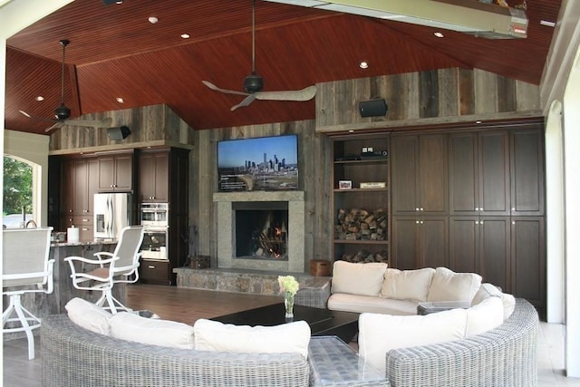 living room featuring high vaulted ceiling, a stone fireplace, ceiling fan, and wooden ceiling