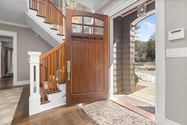 entryway with crown molding and dark wood-type flooring