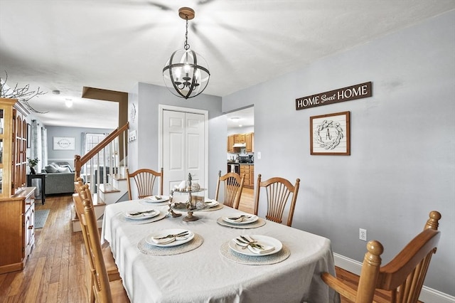 dining space featuring baseboards, stairs, hardwood / wood-style floors, and an inviting chandelier