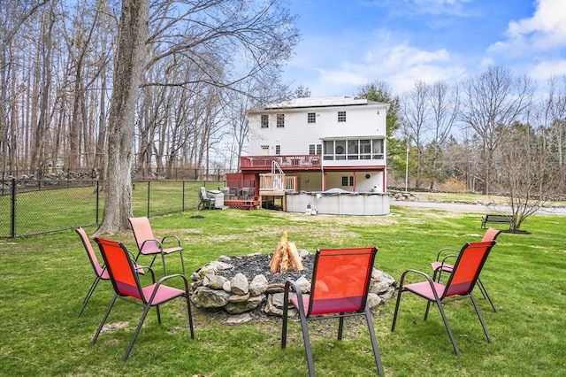 rear view of house featuring a hot tub, fence, a deck, an outdoor fire pit, and a sunroom