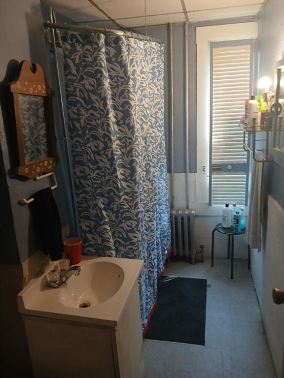 full bathroom featuring a drop ceiling, a shower with shower curtain, vanity, and radiator heating unit