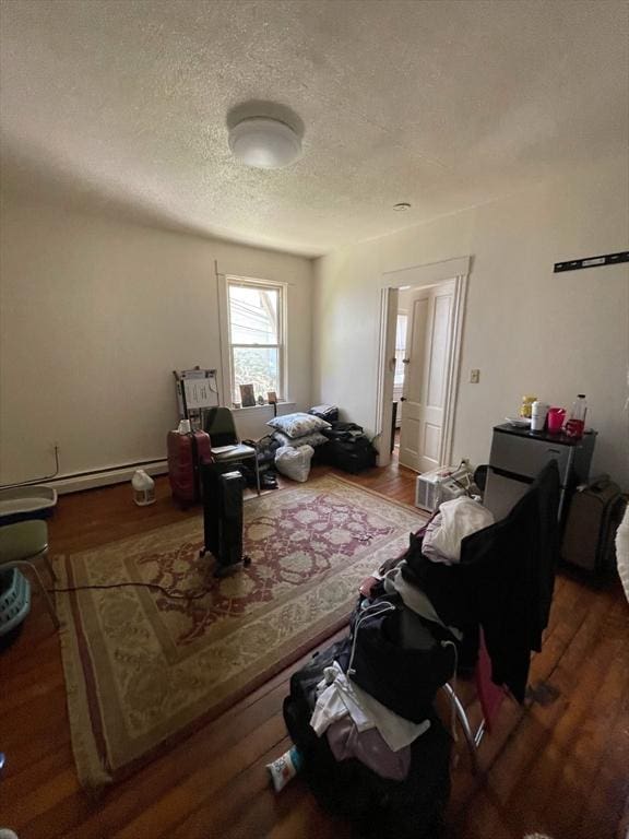 living area featuring a baseboard radiator, a textured ceiling, and wood finished floors