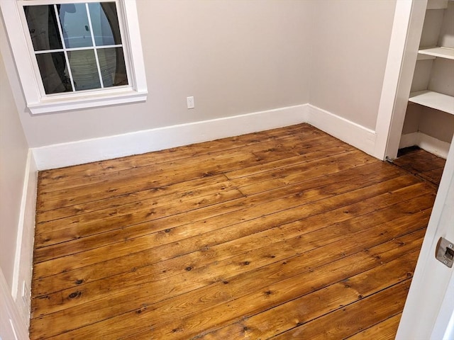 spare room with hardwood / wood-style floors and built in features