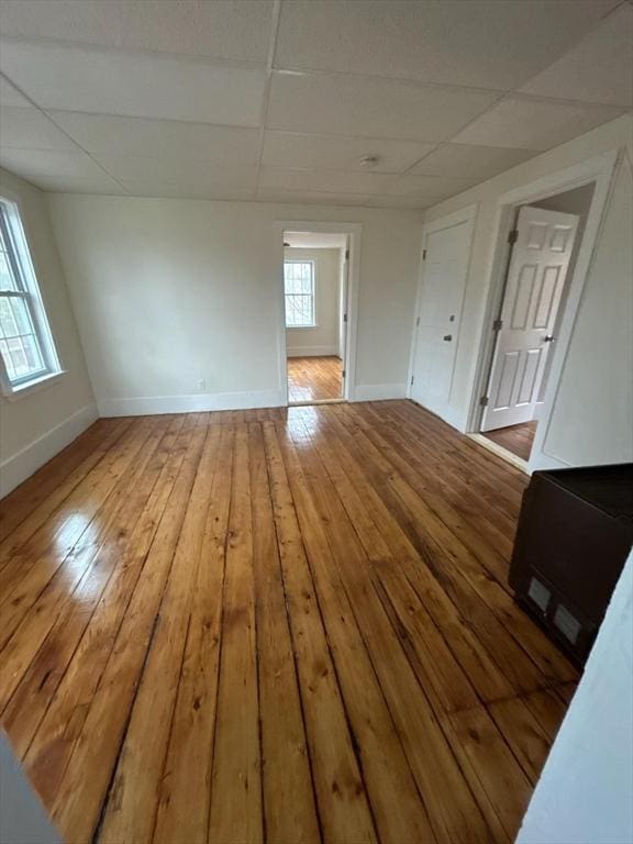 spare room featuring a paneled ceiling and light hardwood / wood-style flooring