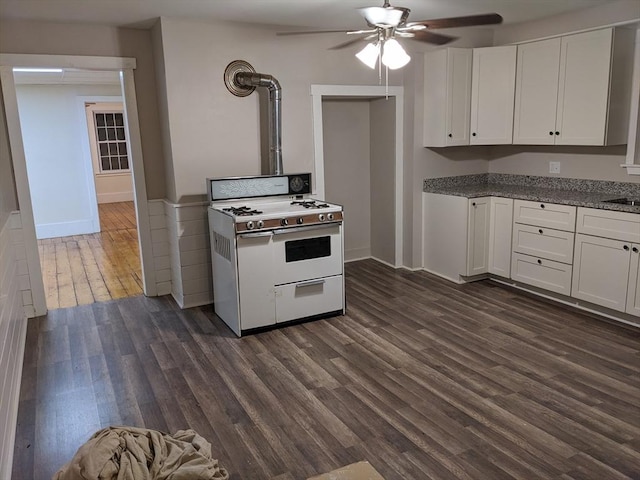 kitchen featuring ceiling fan, dark wood-type flooring, white cabinetry, and gas range gas stove