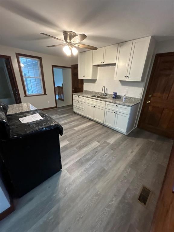 kitchen with ceiling fan, sink, white cabinets, and light wood-type flooring