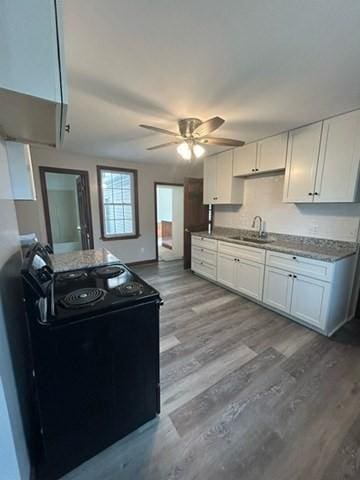 kitchen with white cabinetry, light hardwood / wood-style floors, sink, ceiling fan, and electric range