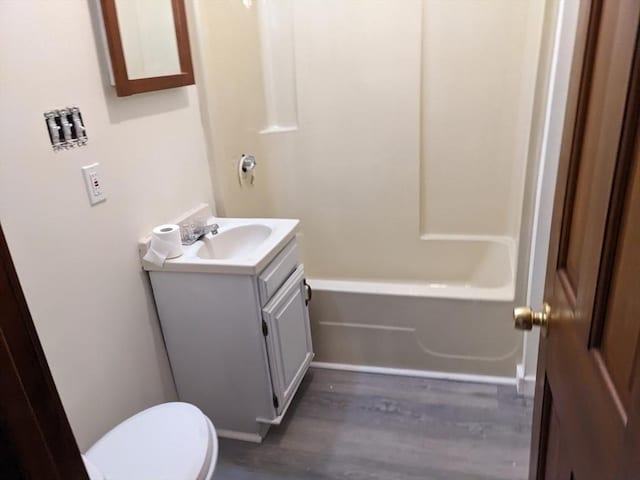 full bathroom featuring toilet, hardwood / wood-style floors, vanity, and washtub / shower combination