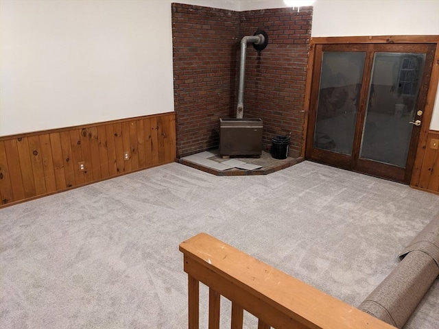 living room featuring wood walls, a wood stove, and light carpet