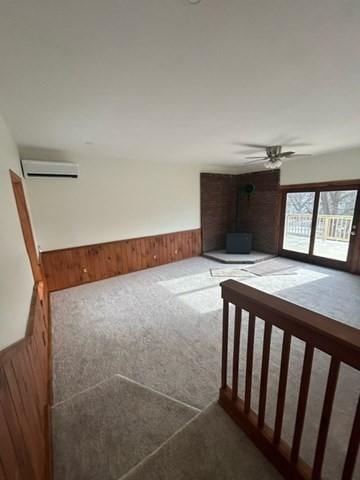 interior space featuring ceiling fan, a wood stove, wood walls, and an AC wall unit