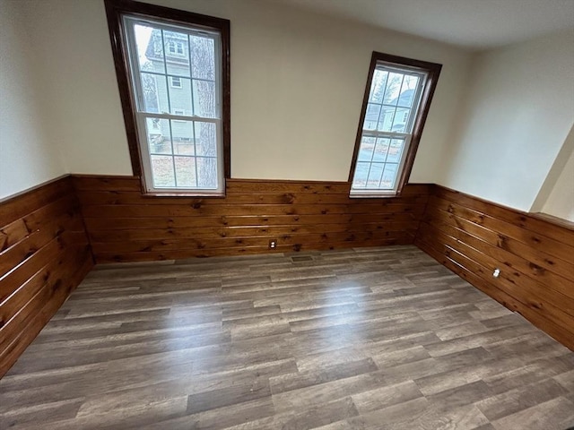 spare room with dark hardwood / wood-style flooring and wood walls