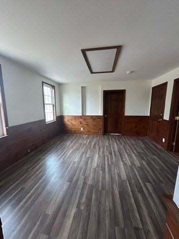 spare room with dark hardwood / wood-style floors and wood walls