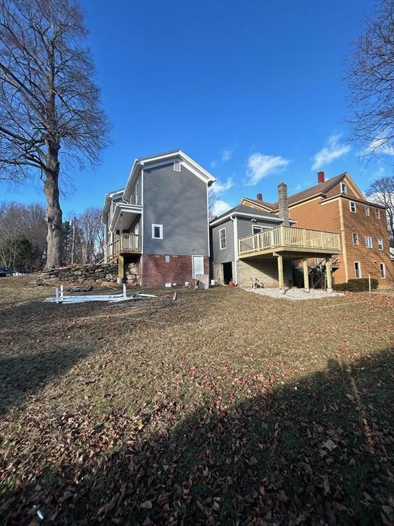 rear view of house featuring a lawn and a wooden deck