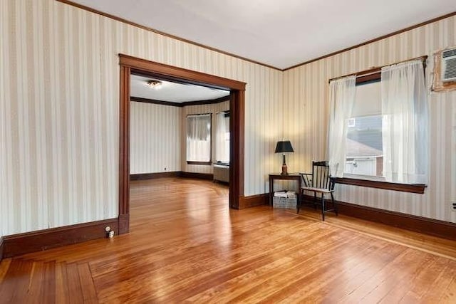 unfurnished room with baseboards, hardwood / wood-style flooring, ornamental molding, and wallpapered walls