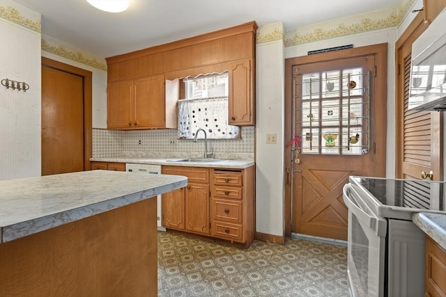 kitchen with a sink, white appliances, light countertops, brown cabinetry, and decorative backsplash
